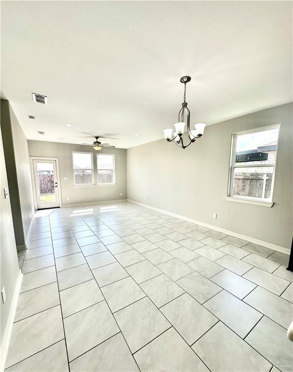 tiled empty room with ceiling fan with notable chandelier