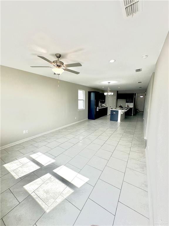 unfurnished living room with light tile patterned flooring and ceiling fan with notable chandelier