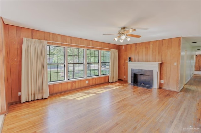 1150 N Bowie St, San Benito, TX 78586 - unfurnished living room with light wood-style floors, wooden walls, healthy amount of natural light, and a tiled fireplace