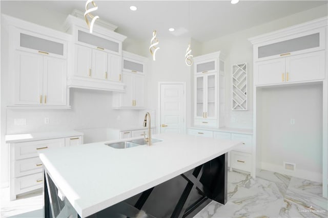 kitchen with a kitchen bar, sink, pendant lighting, a center island with sink, and white cabinets