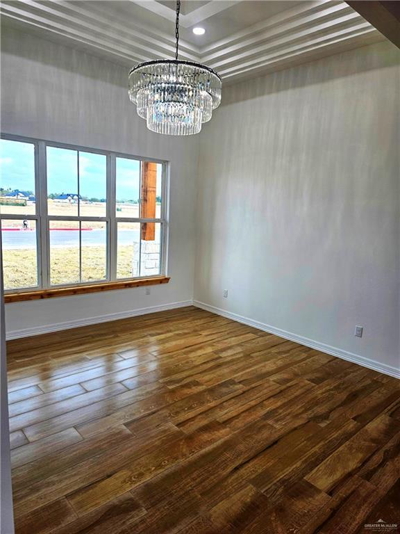 empty room with dark hardwood / wood-style floors and an inviting chandelier