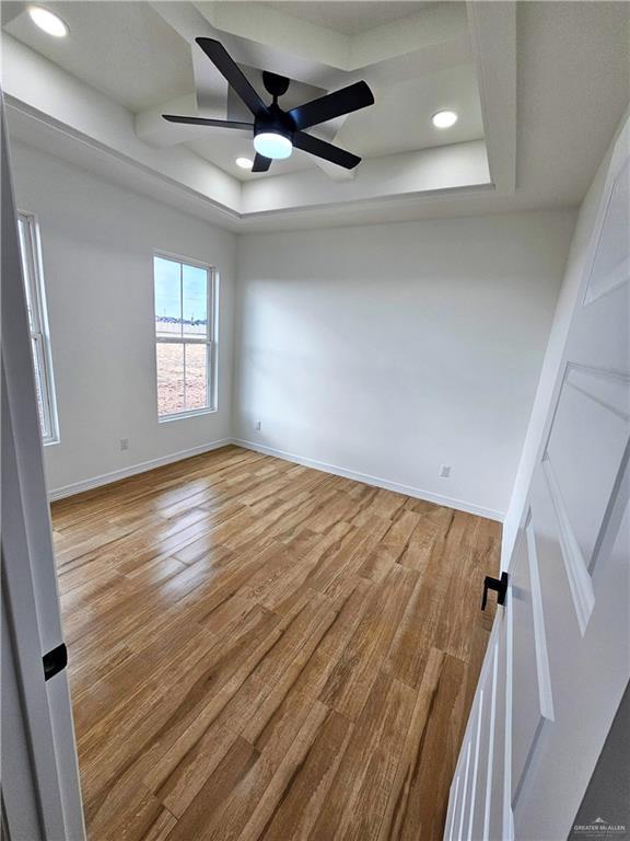 spare room with hardwood / wood-style flooring, ceiling fan, and a tray ceiling