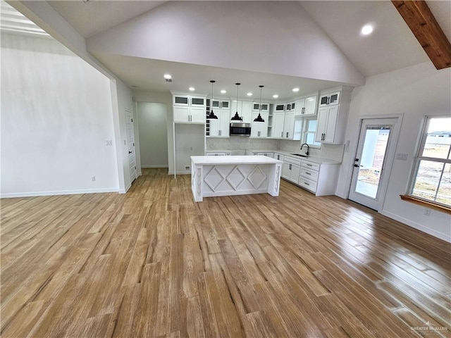 kitchen featuring white cabinetry, decorative light fixtures, a center island, and sink