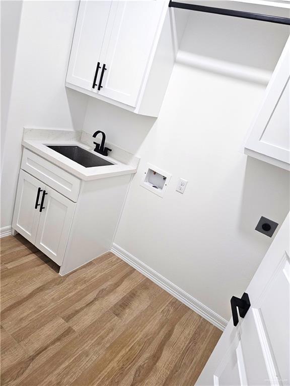 washroom featuring hookup for an electric dryer, sink, and light wood-type flooring