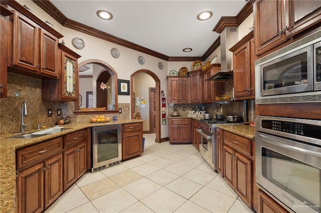 kitchen with appliances with stainless steel finishes, sink, backsplash, wall chimney range hood, and beverage cooler