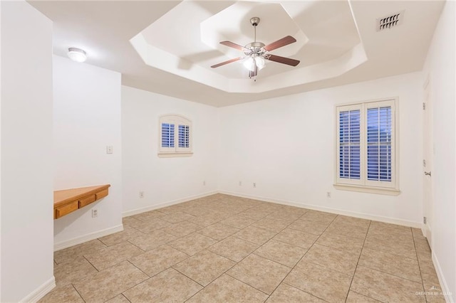 tiled spare room with a raised ceiling and ceiling fan