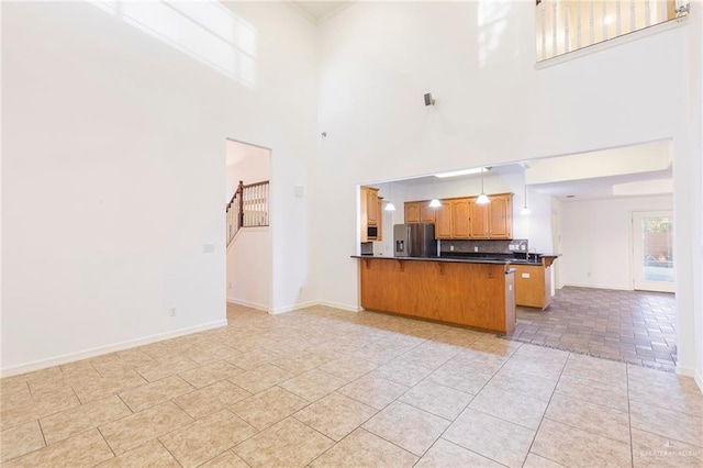 kitchen with a kitchen breakfast bar, hanging light fixtures, a towering ceiling, appliances with stainless steel finishes, and kitchen peninsula