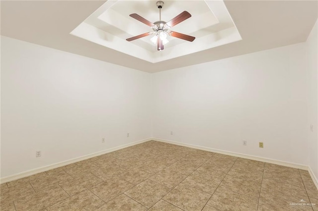 tiled spare room with a tray ceiling and ceiling fan