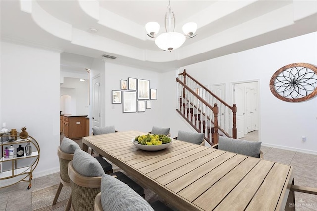 tiled dining area with a raised ceiling and an inviting chandelier