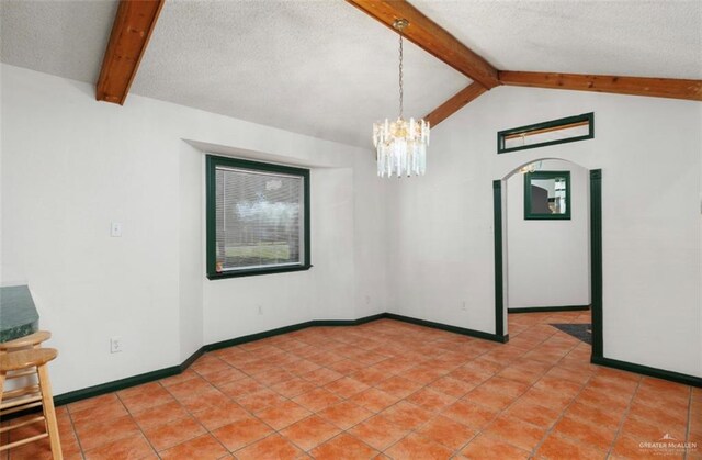 empty room featuring vaulted ceiling with beams, a wealth of natural light, a chandelier, and a textured ceiling