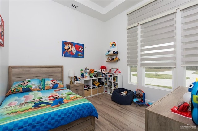 bedroom with light wood finished floors and visible vents