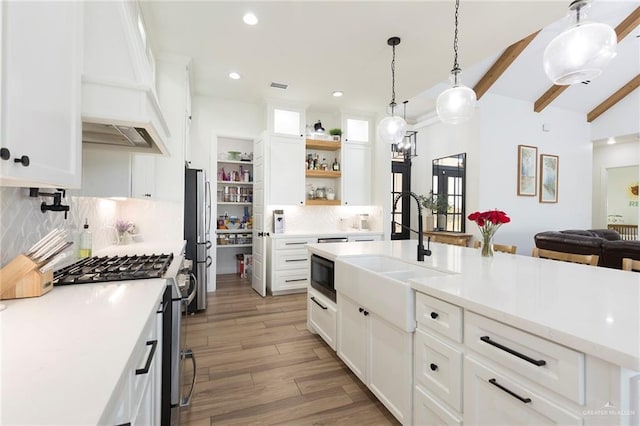 kitchen with white cabinets, stainless steel appliances, light countertops, and a sink