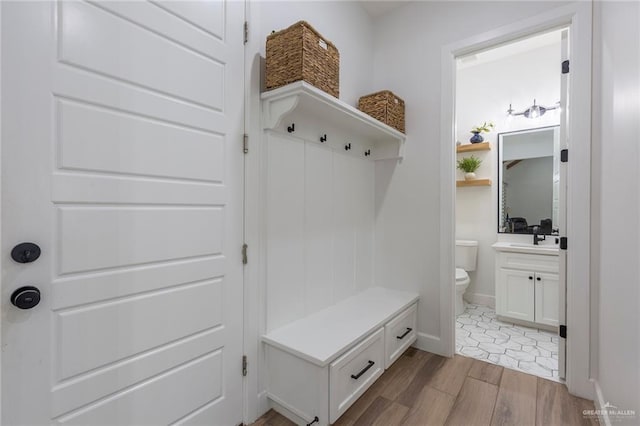 mudroom with light wood-style floors, a sink, and baseboards