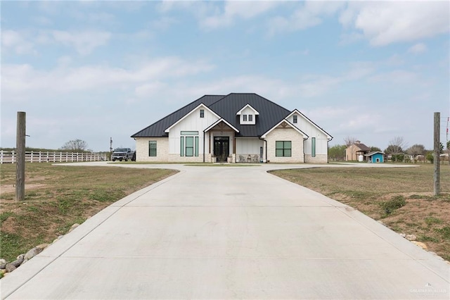 modern farmhouse style home featuring a standing seam roof, driveway, and board and batten siding