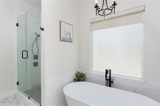 bathroom featuring a freestanding tub, a marble finish shower, tile walls, and an inviting chandelier