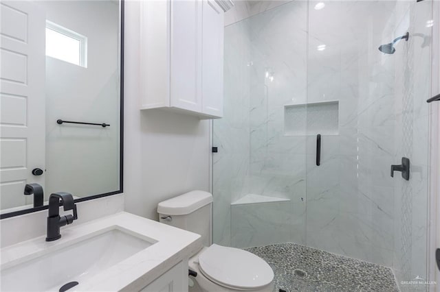 bathroom with toilet, a marble finish shower, and vanity