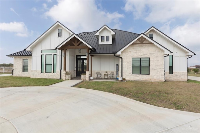 modern farmhouse style home with board and batten siding, a front yard, a standing seam roof, and metal roof