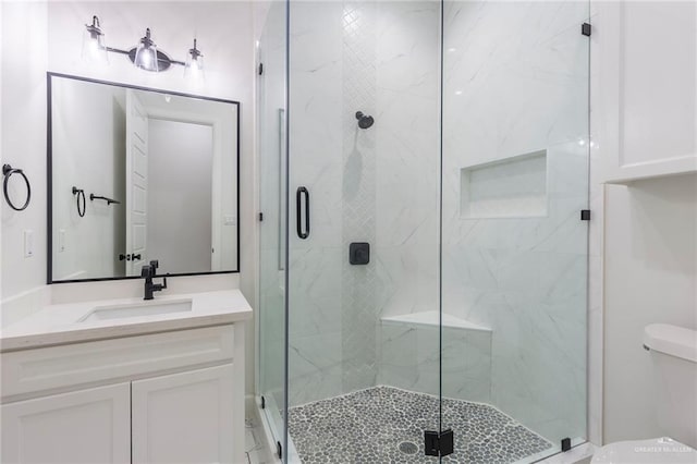 bathroom with toilet, a shower stall, and vanity