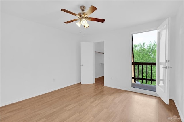 empty room with baseboards, ceiling fan, and light wood-style flooring