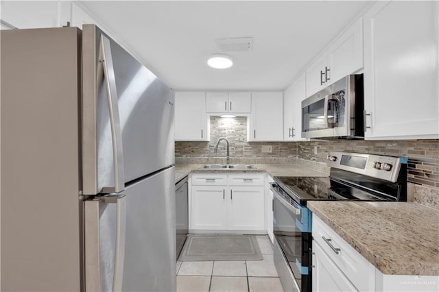 kitchen featuring visible vents, light tile patterned floors, a sink, backsplash, and stainless steel appliances
