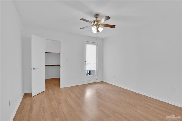 unfurnished bedroom with ceiling fan, light wood-type flooring, baseboards, a closet, and a spacious closet
