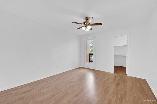 empty room featuring light wood-type flooring, a ceiling fan, and baseboards
