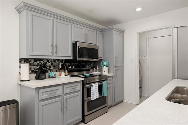3408 Whiskey Dr, Pharr, TX 78577 - kitchen with appliances with stainless steel finishes, gray cabinetry, light countertops, light tile patterned floors, and decorative backsplash