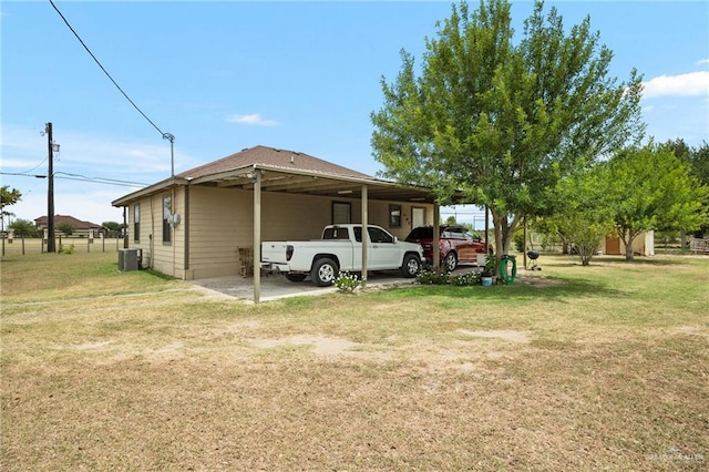 view of side of property featuring fence, central air condition unit, a yard, and a carport