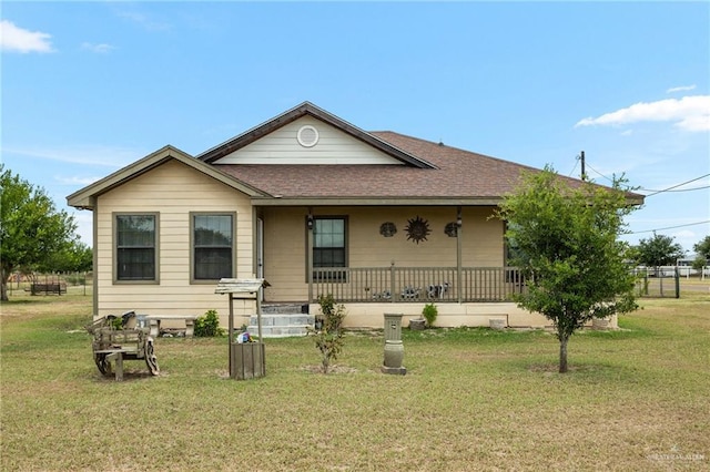 view of front of home with roof with shingles, covered porch, and a front lawn