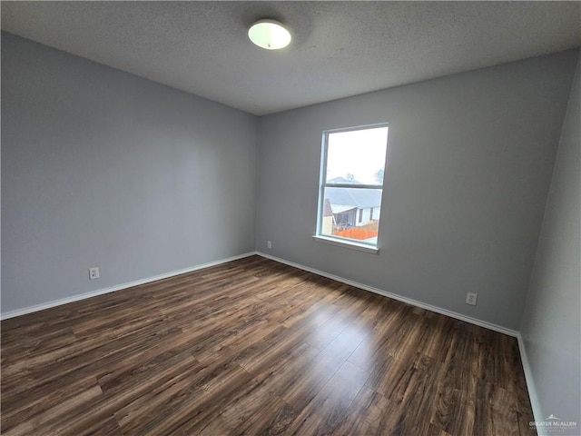 spare room featuring dark hardwood / wood-style floors and a textured ceiling