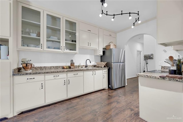 2600 Northgate Ln, Mcallen, TX 78504 - kitchen with freestanding refrigerator, dark wood-style floors, arched walkways, light stone counters, and a sink