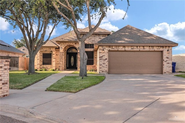 2600 Northgate Ln, Mcallen, TX 78504 - view of front of home featuring a garage, a front lawn, fence, brick siding, and driveway