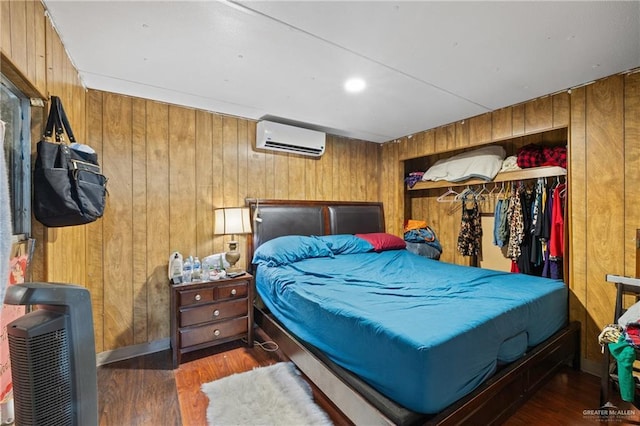 bedroom featuring heating unit, a wall unit AC, dark hardwood / wood-style floors, and wood walls