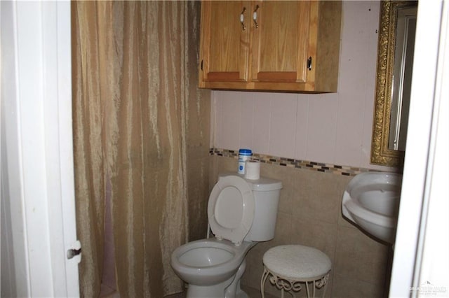 bathroom with toilet and tile walls