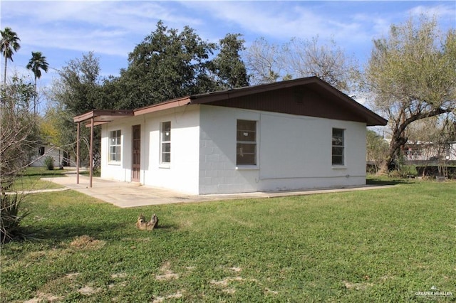 view of property exterior with a patio and a lawn