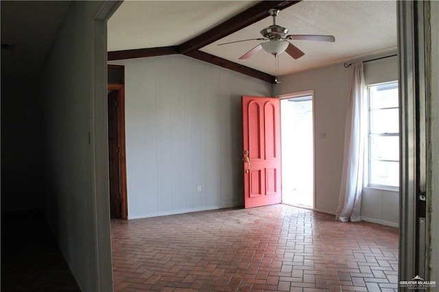 unfurnished room with ceiling fan, a healthy amount of sunlight, and vaulted ceiling with beams