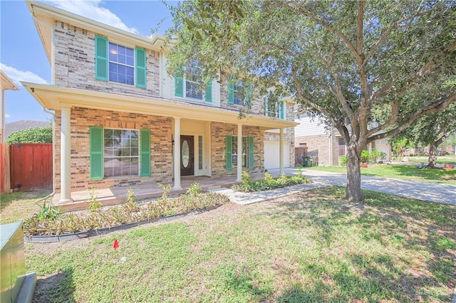 view of front of house featuring covered porch, a garage, and a front lawn