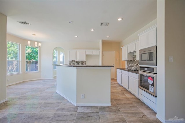 kitchen with white cabinetry, decorative backsplash, a kitchen island with sink, and appliances with stainless steel finishes