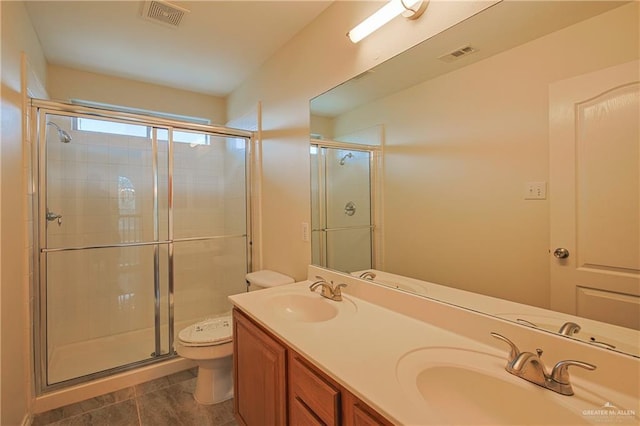 bathroom with tile patterned floors, vanity, a shower with shower door, and toilet