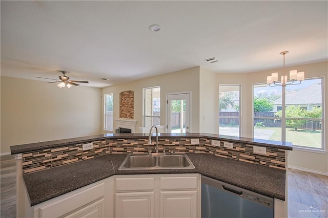 kitchen with a wealth of natural light, ceiling fan with notable chandelier, sink, dishwasher, and white cabinetry