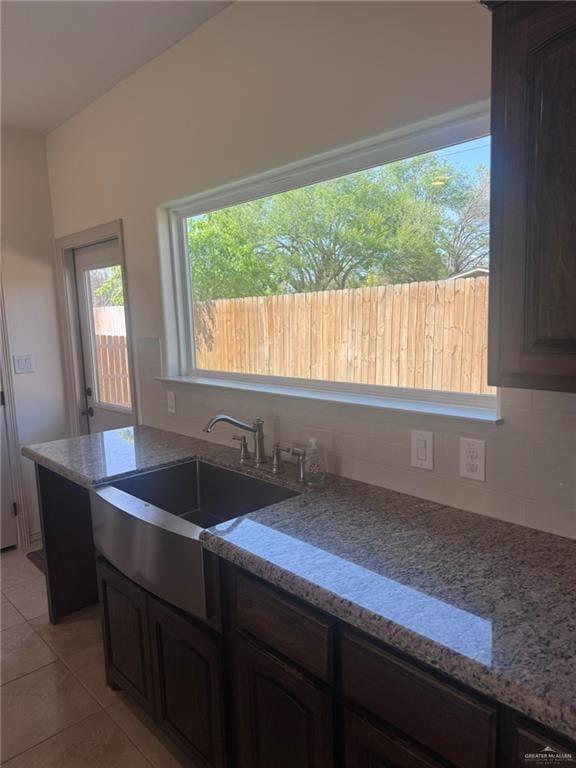 kitchen featuring light stone countertops, backsplash, a sink, and light tile patterned flooring