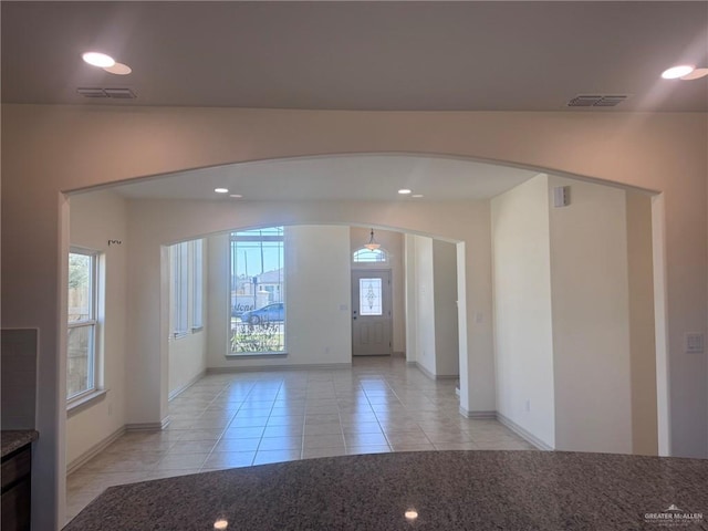 foyer entrance with light tile patterned floors, visible vents, arched walkways, and recessed lighting