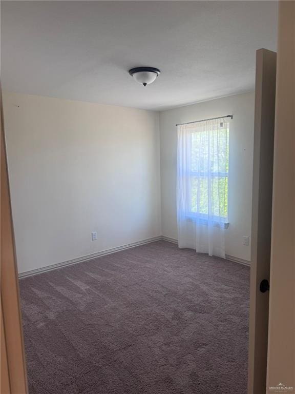 spare room featuring carpet and baseboards