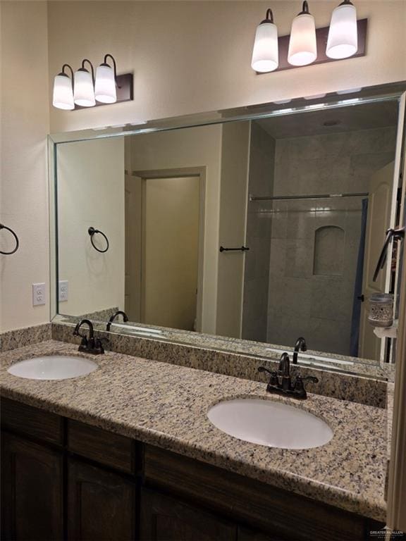 full bath featuring double vanity, a sink, and a shower stall