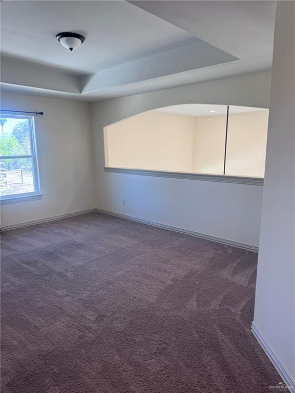 carpeted empty room with baseboards and a tray ceiling