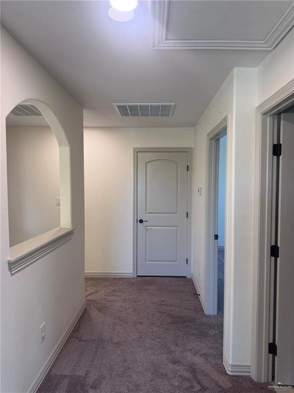 corridor featuring arched walkways, carpet floors, visible vents, and baseboards