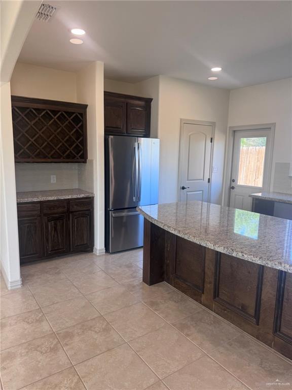 kitchen featuring backsplash, dark brown cabinetry, stainless steel appliances, sink, and a kitchen island