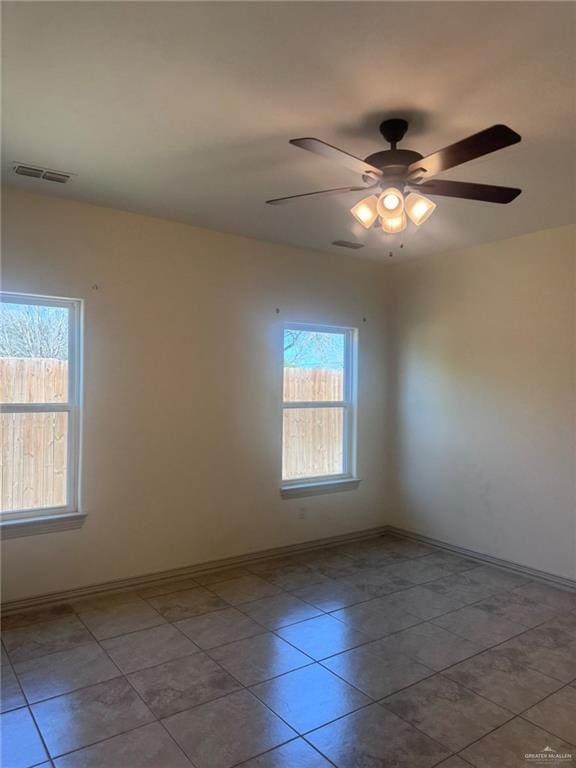 unfurnished room with baseboards, a wealth of natural light, visible vents, and a ceiling fan