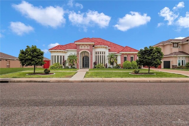 1410 Lobelia St, Weslaco, TX 78599 - mediterranean / spanish house featuring driveway, a front yard, a tile roof, and stucco siding