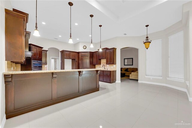 1410 Lobelia St, Weslaco, TX 78599 - kitchen featuring arched walkways, a peninsula, backsplash, decorative light fixtures, and recessed lighting